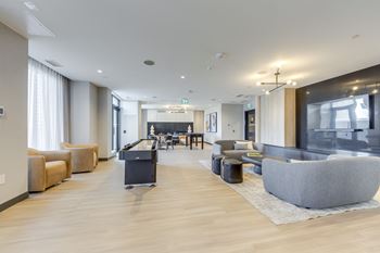 A spacious living room with a grey sofa and wooden flooring.
